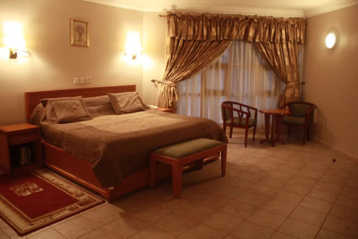 Ein Schlafzimmer mit einem großen Bett, Nachttischen, einem Sessel und einem kleinen Tisch.