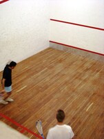 Una cancha de squash con piso de madera y líneas divisorias rojas.