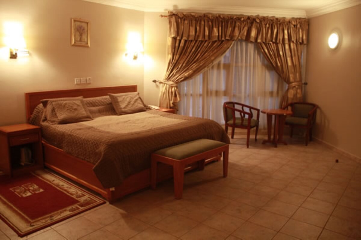 A bedroom with a large bed, bedside tables, a chair, and a small table.