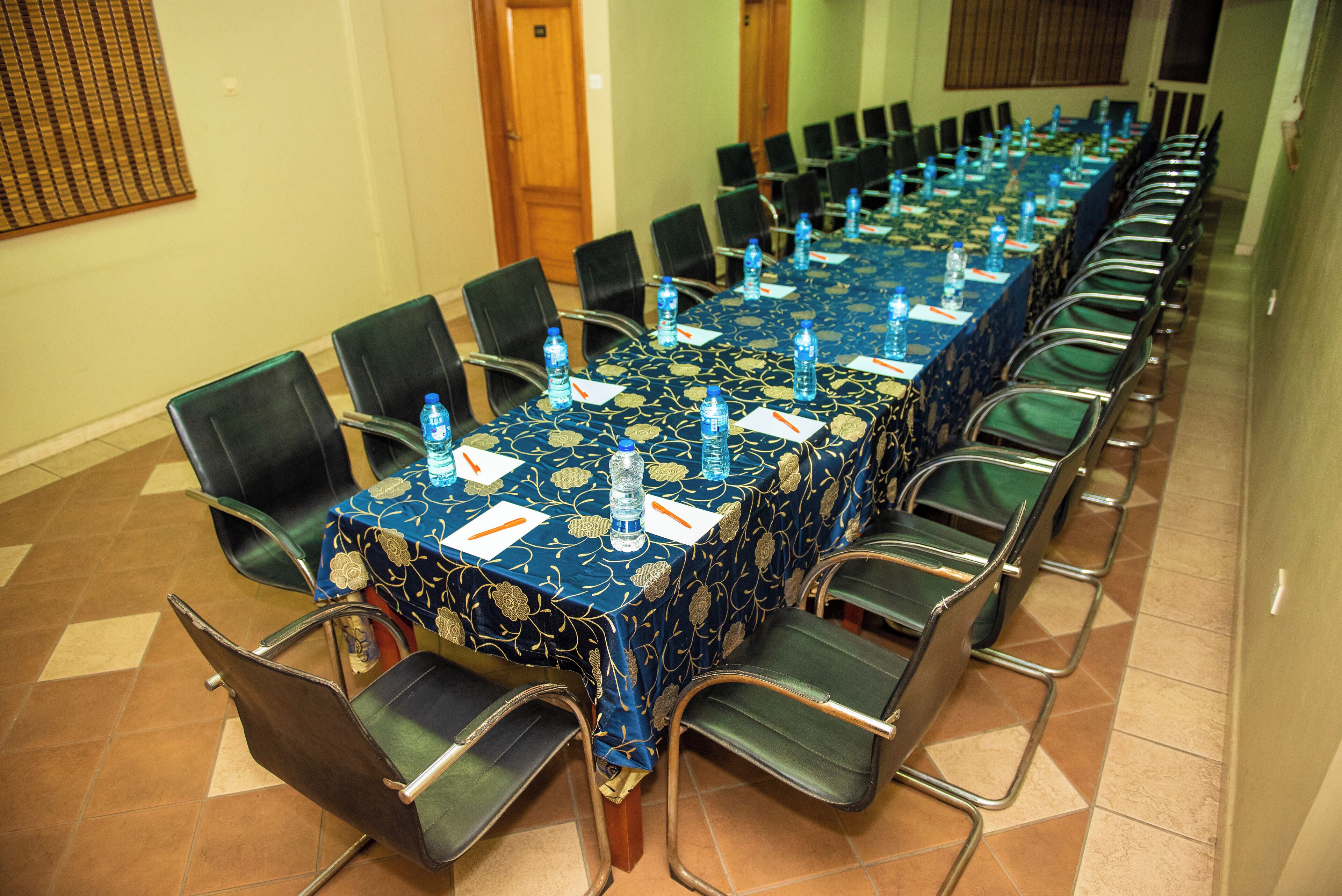 Een vergaderruimte met een lange tafel, stoelen en waterflesjes.