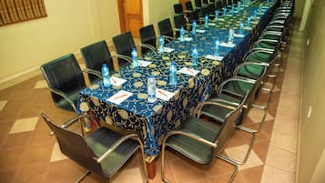 Een vergaderruimte met een lange tafel, stoelen en waterflesjes.