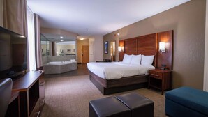 A hotel room with a bed, a desk, a TV, a bathroom, and a seating area.