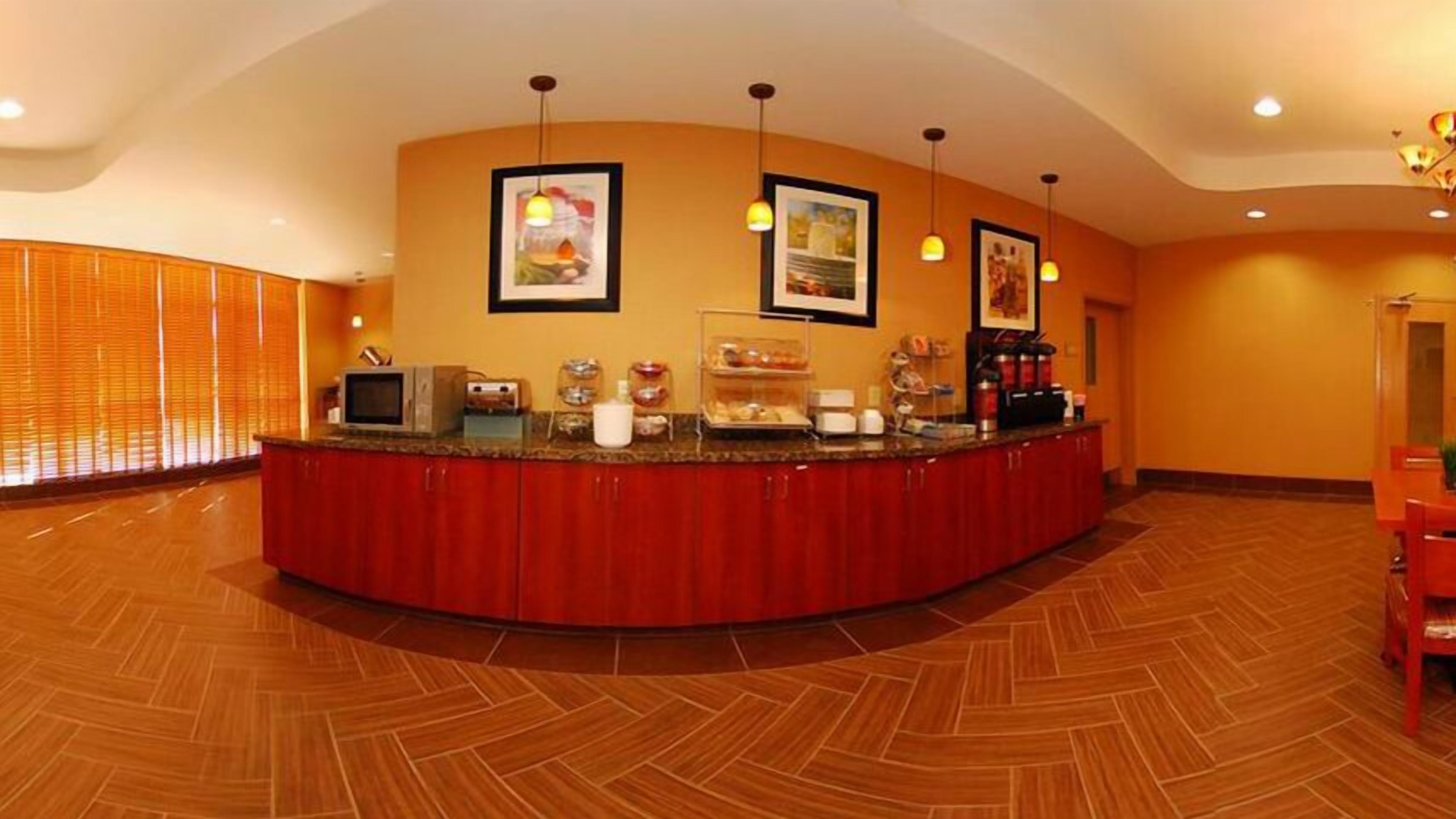 A reception area with a curved counter, framed pictures on the wall, and a coffee station.