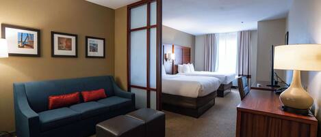 Una habitación de hotel con una cama, un sofá, un escritorio y un televisor.