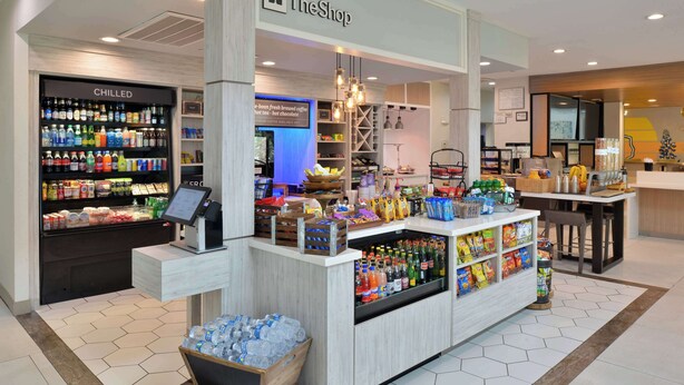 A TheShop store with chilled beverages, snacks, and a coffee station. - Hilton Garden Inn Denton (Denton)
