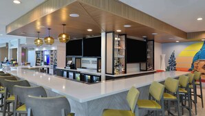 A modern bar area with a central counter, bar stools, and overhead lighting. - Hilton Garden Inn Denton (Denton)