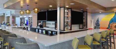 A modern bar area with a central counter, bar stools, and overhead lighting.