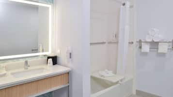 A modern bathroom with a large mirror, a sink, a shower, and a towel rack.