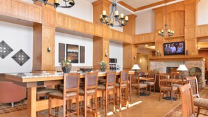 A spacious dining area with wooden furniture, a bar, and a television screen. - Hampton Inn & Suites Buffalo (Buffalo)