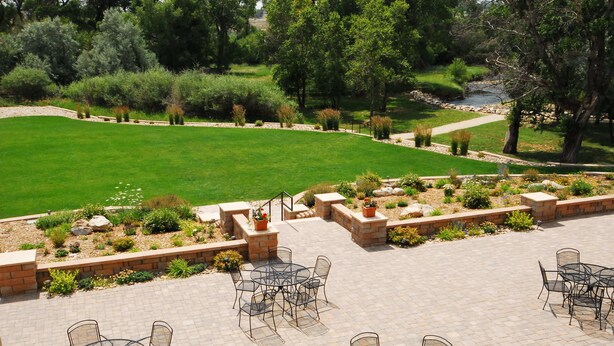 A patio area with outdoor seating and a view of a well-maintained lawn and garden. - Hampton Inn & Suites Buffalo (Buffalo)