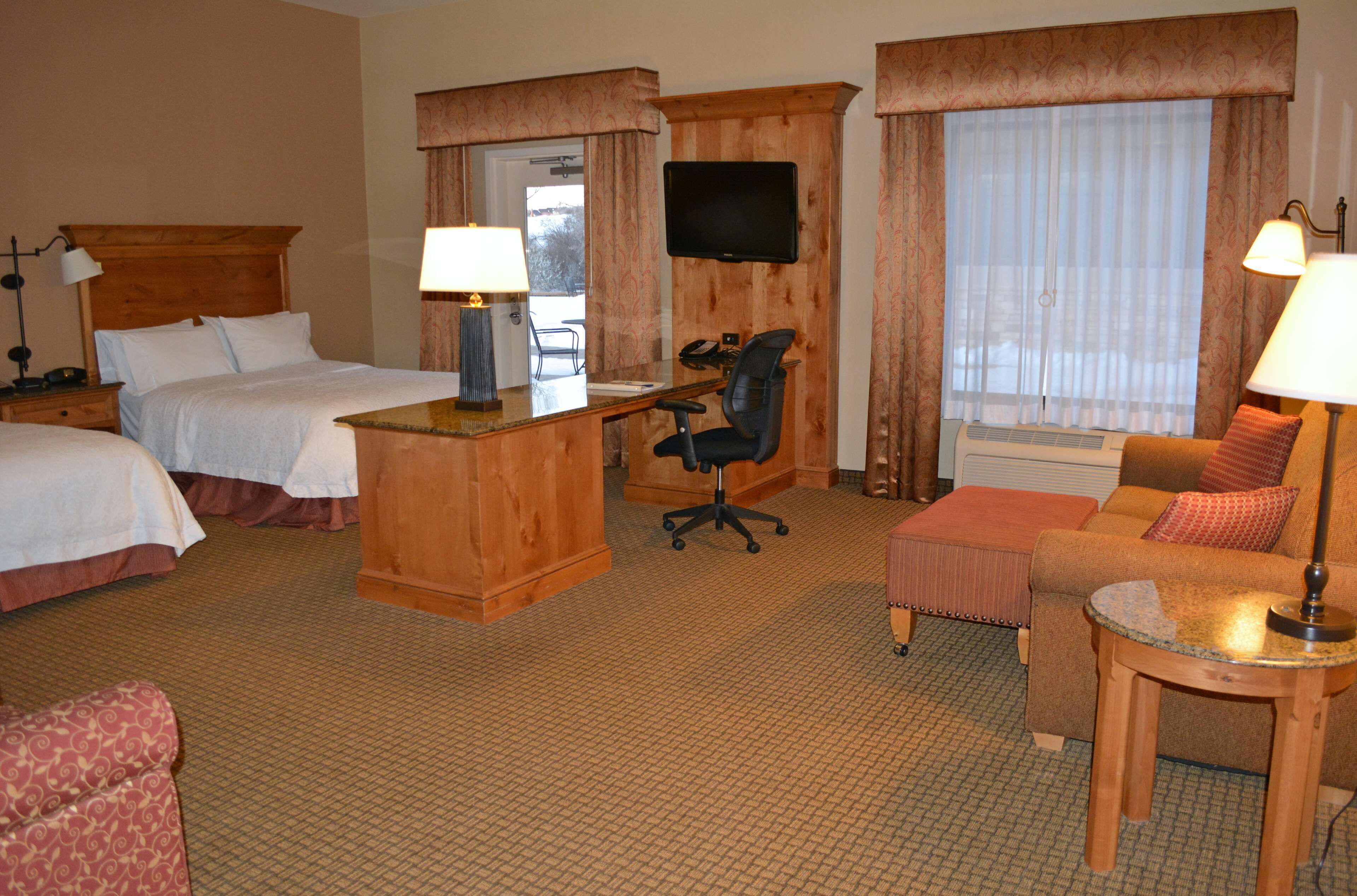 Habitación de hotel con dos camas, un escritorio con silla, televisor y sofá.