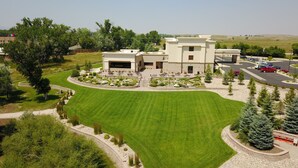 A modern building with a large lawn, a parking lot, and a small garden area. - Hampton Inn & Suites Buffalo (Buffalo)