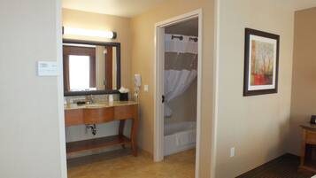 A hotel bathroom with a sink, mirror, and shower curtain.
