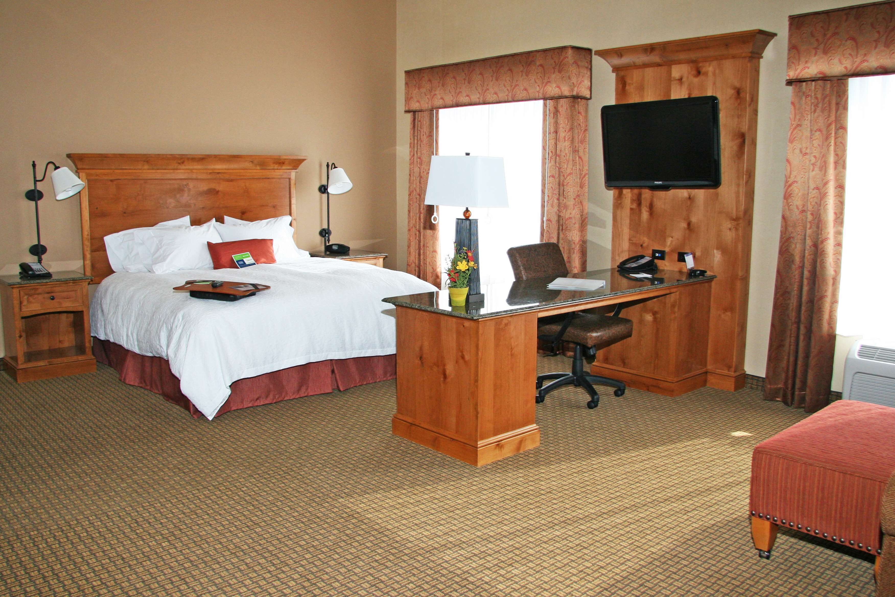 Una habitación de hotel con cama, escritorio, silla y televisión.