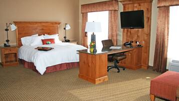 Una habitación de hotel con cama, escritorio, silla y televisión.