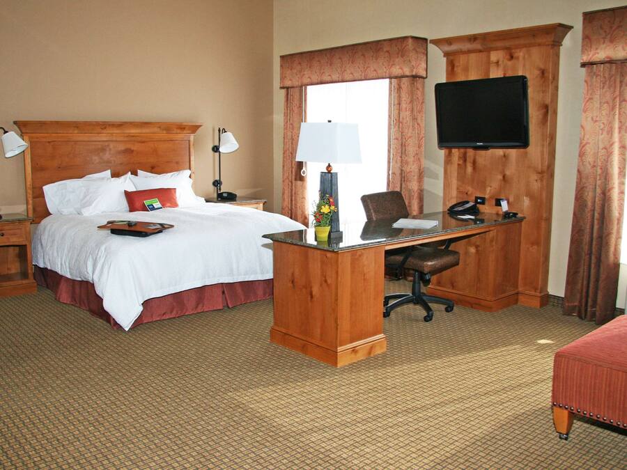 Una habitación de hotel con cama, escritorio, silla y televisión.