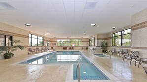 An indoor swimming pool with tiled flooring, chairs, and potted plants. - Hampton Inn & Suites Buffalo (Buffalo)