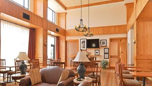 A spacious lobby with a high ceiling, wooden paneling, a chandelier, a television, and a variety of seating arrangements including sofas and chairs. - Hampton Inn & Suites Buffalo (Buffalo)