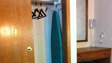 Une salle de bain avec une porte en bois, un porte-serviettes avec une serviette, un miroir et un lavabo avec un tabouret en bois.