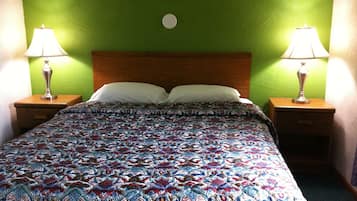 A bed with a patterned bedspread, two bedside lamps, and a green wall.