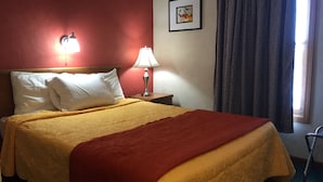 A hotel room with a bed, two bedside lamps, a framed picture on the wall, and a window with curtains. - East Street Inn & Suites Tipton (Tipton)
