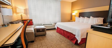 A hotel room with a bed, desk, chair, and a television.
