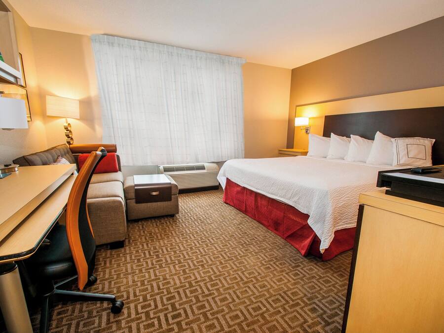 Ein Hotelzimmer mit Bett, Schreibtisch, Stuhl und Fernseher.