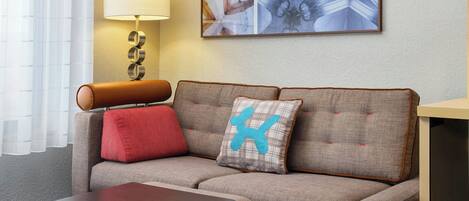 Ein modernes Wohnzimmer mit Sofa, Couchtisch, Lampe und Kunstwerken an der Wand.