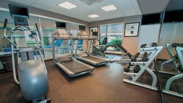 Une salle de sport équipée de tapis de course, d’un vélo elliptique et d’un vélo d’appartement.