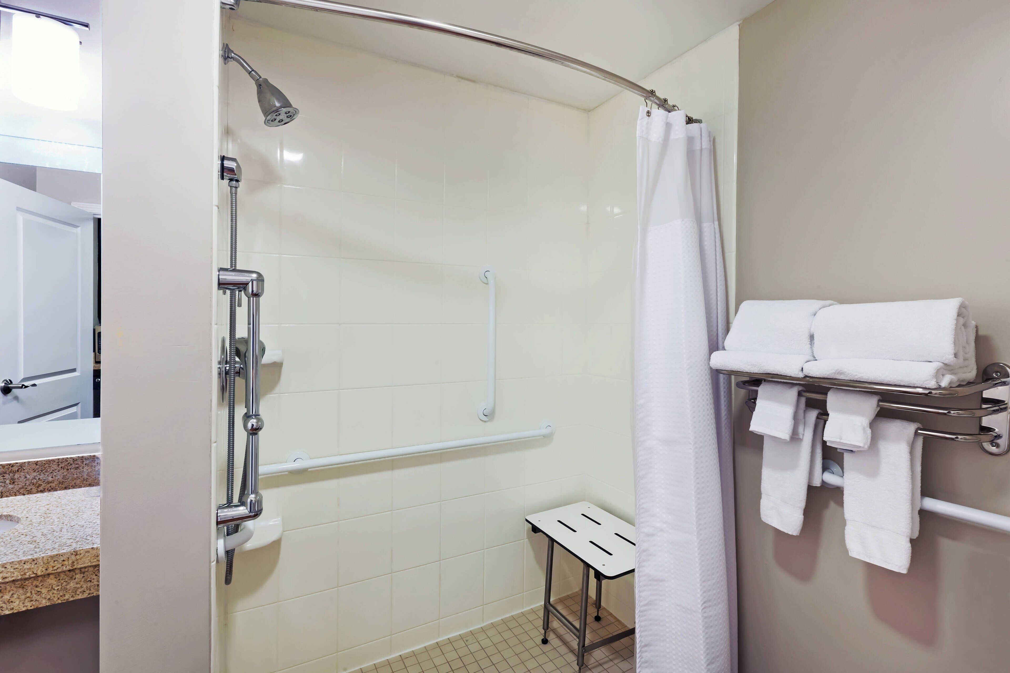 Un baño con ducha, toallero y una mesita.