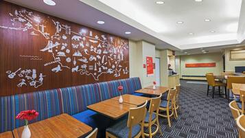 Un restaurante con cabinas, mesas y sillas. Se observa una pared con un mapa y varios iconos.