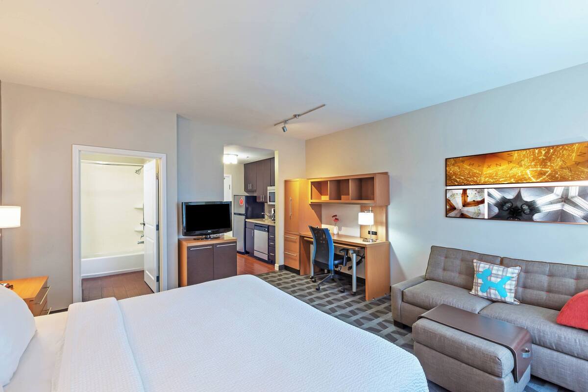 Une chambre d’hôtel comprenant un lit, un bureau, un canapé, une télévision et un espace douche.