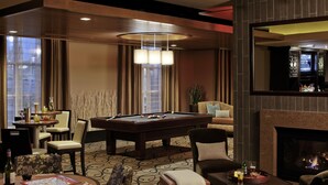 Un hall d’hôtel doté d’une table de billard, d’un coin salon, d’un bar et d’une cheminée.