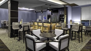 Un espace bar moderne avec des tabourets hauts et une table ronde centrale, entourée de chaises de bar.