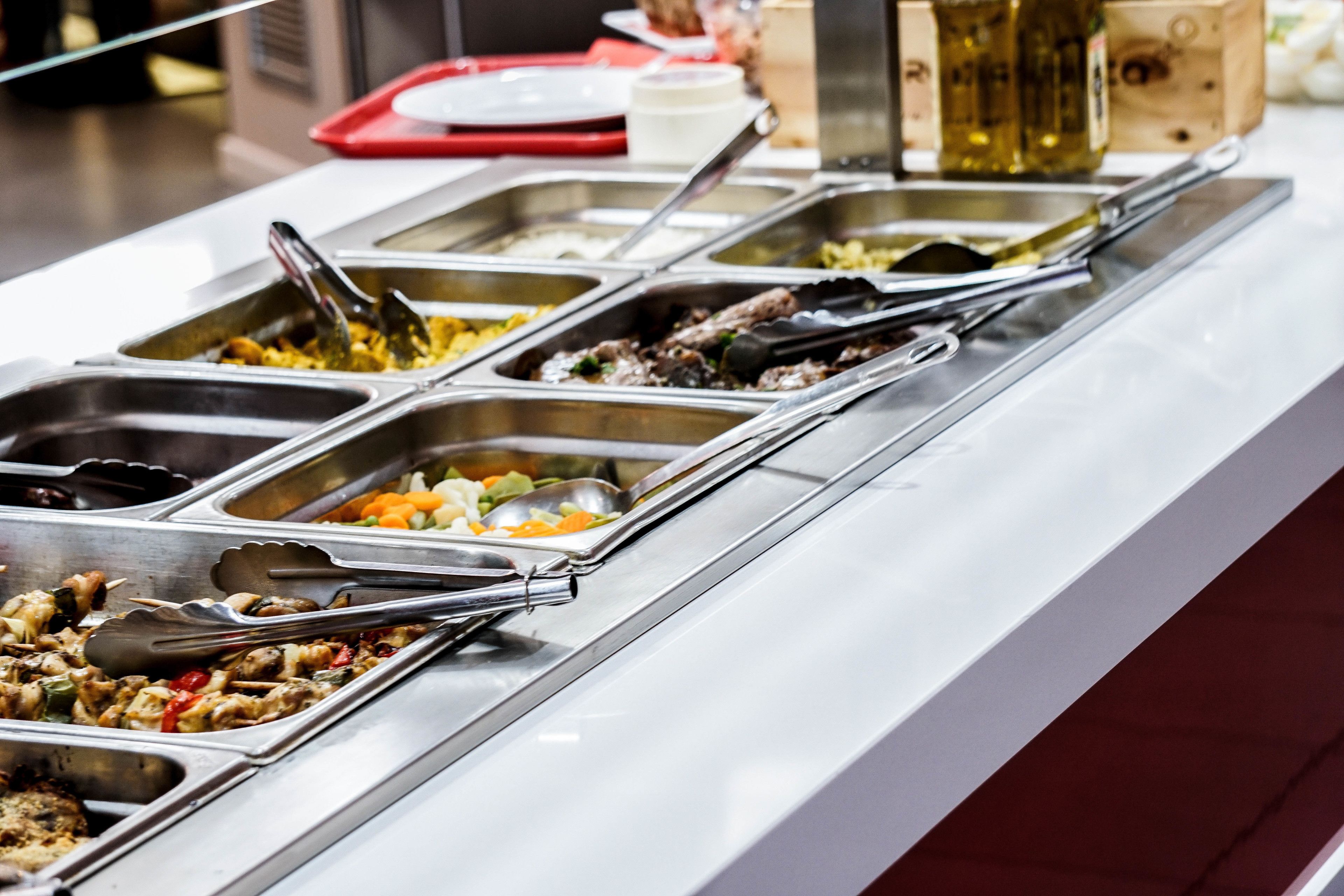A buffet with multiple food stations, each with metal serving utensils.