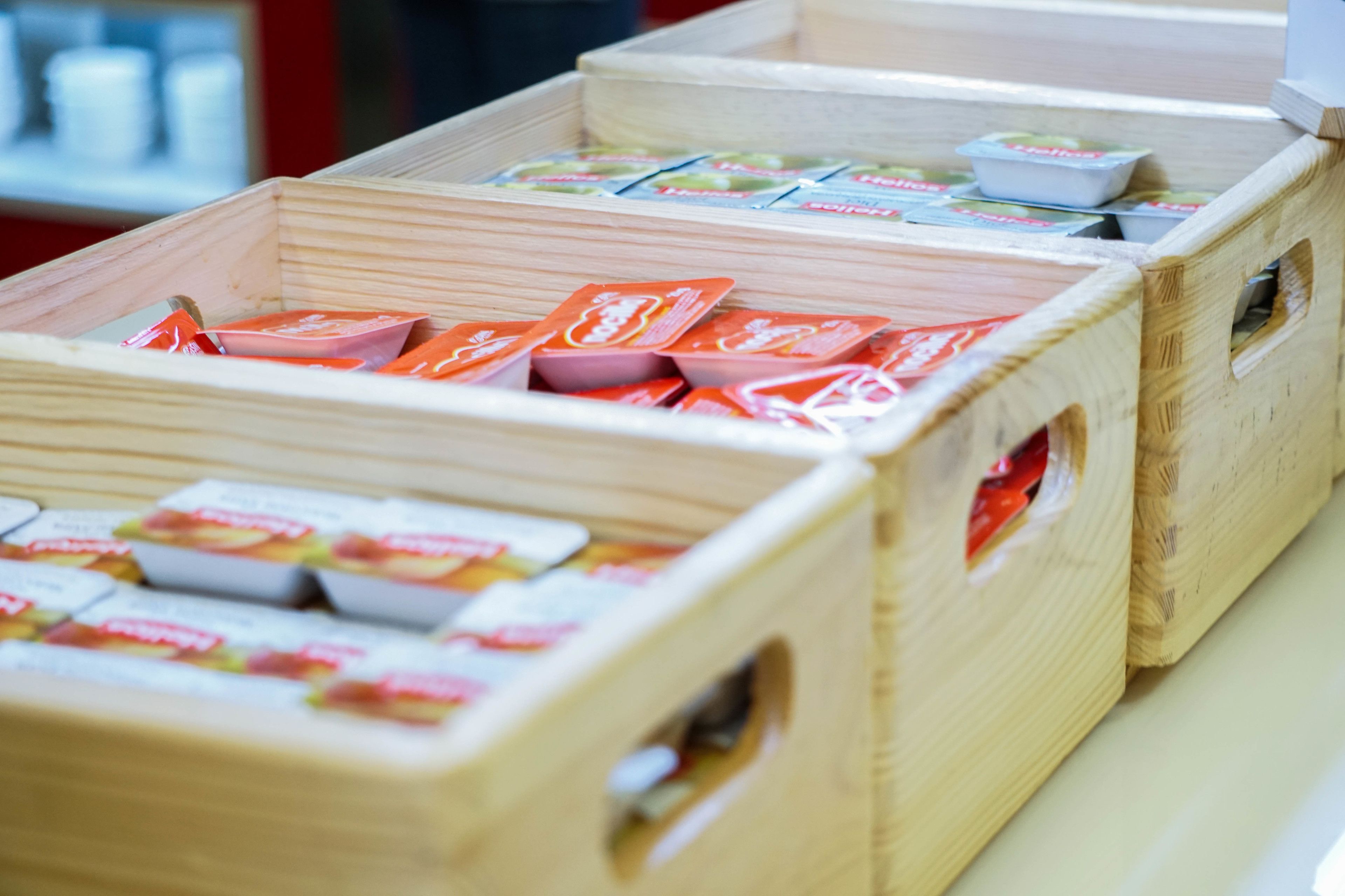 Cajas de madera llenas de productos envasados, presumiblemente alimentos, en un entorno comercial.