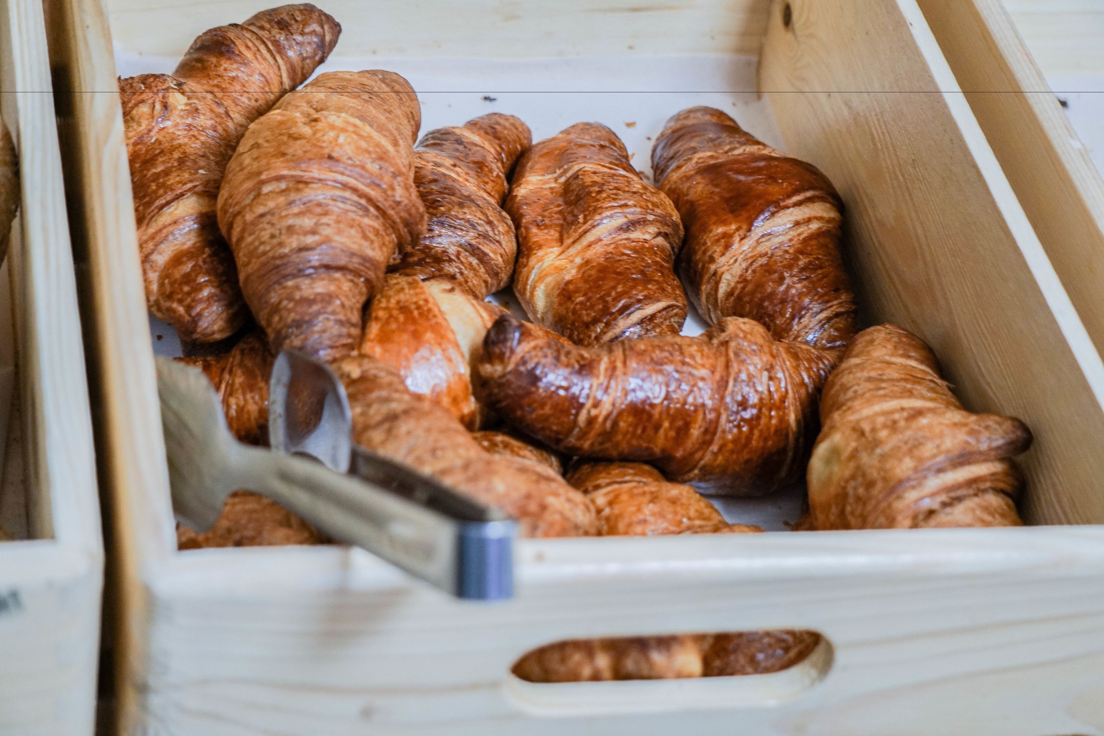 A wooden box containing several croissants.
