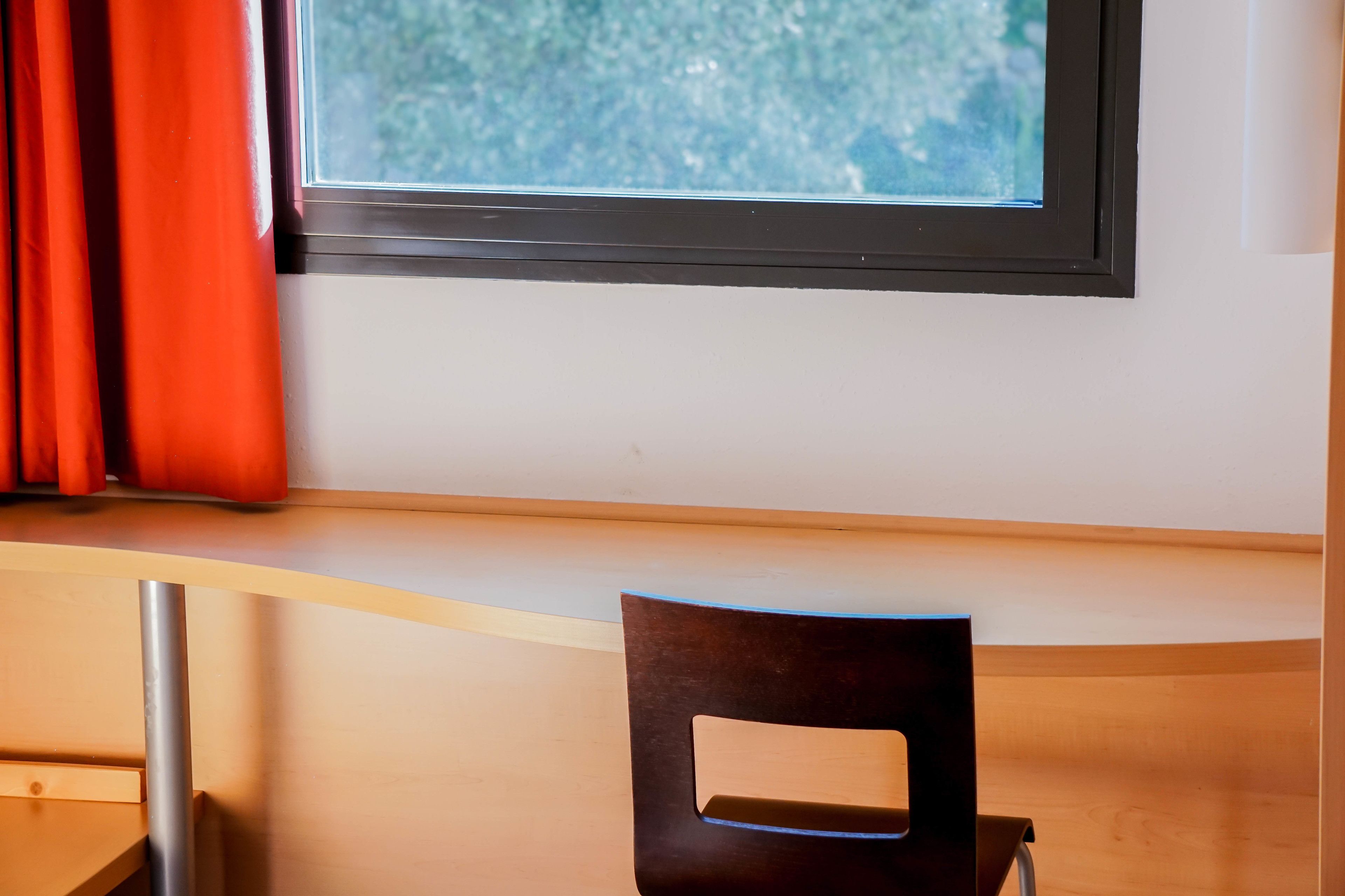 A room with a window, a chair, and a table.