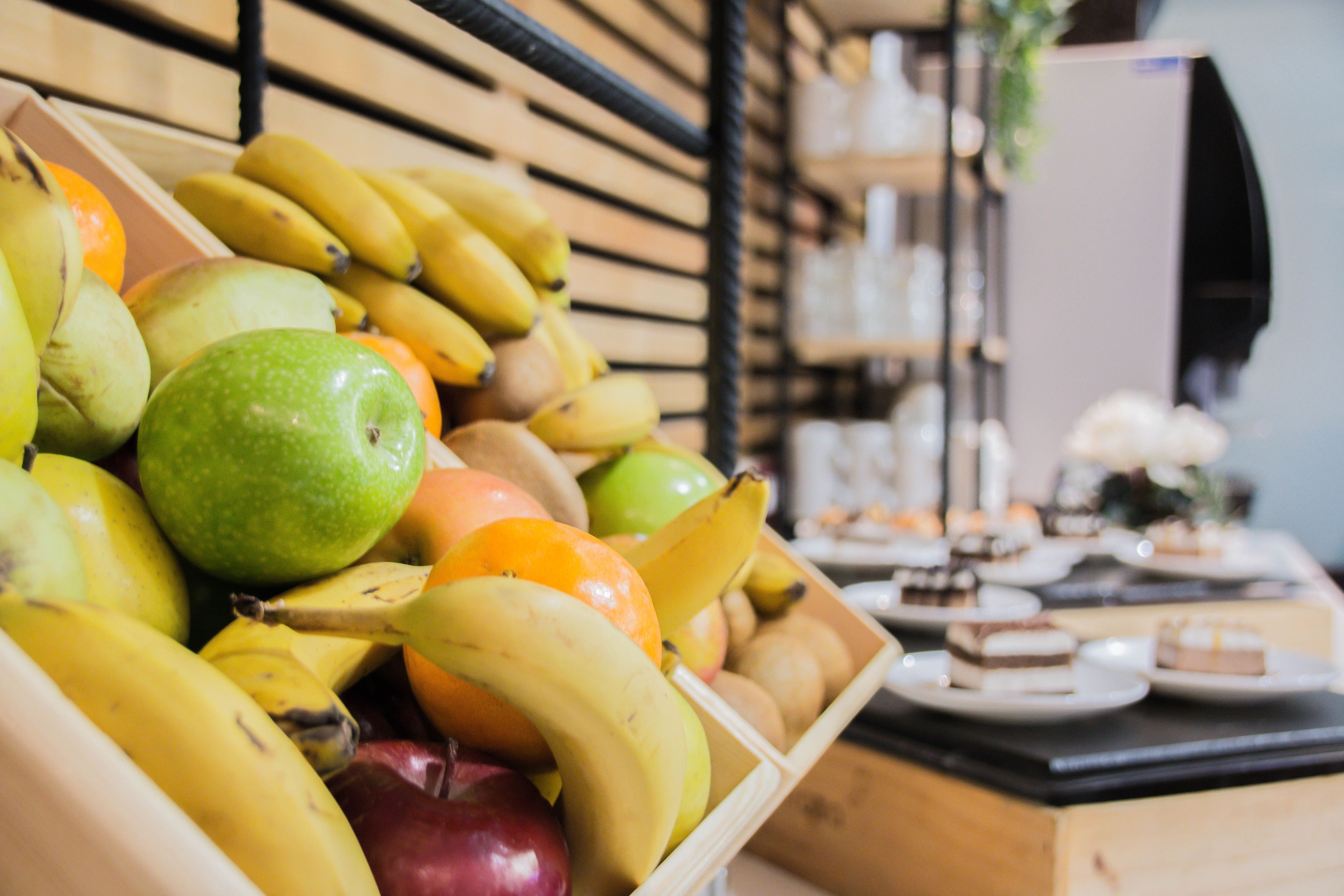 Una caja de madera llena de frutas variadas y un mostrador con postres.