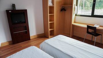 Une chambre avec deux lits, une armoire en bois, une télévision et un bureau avec une chaise.