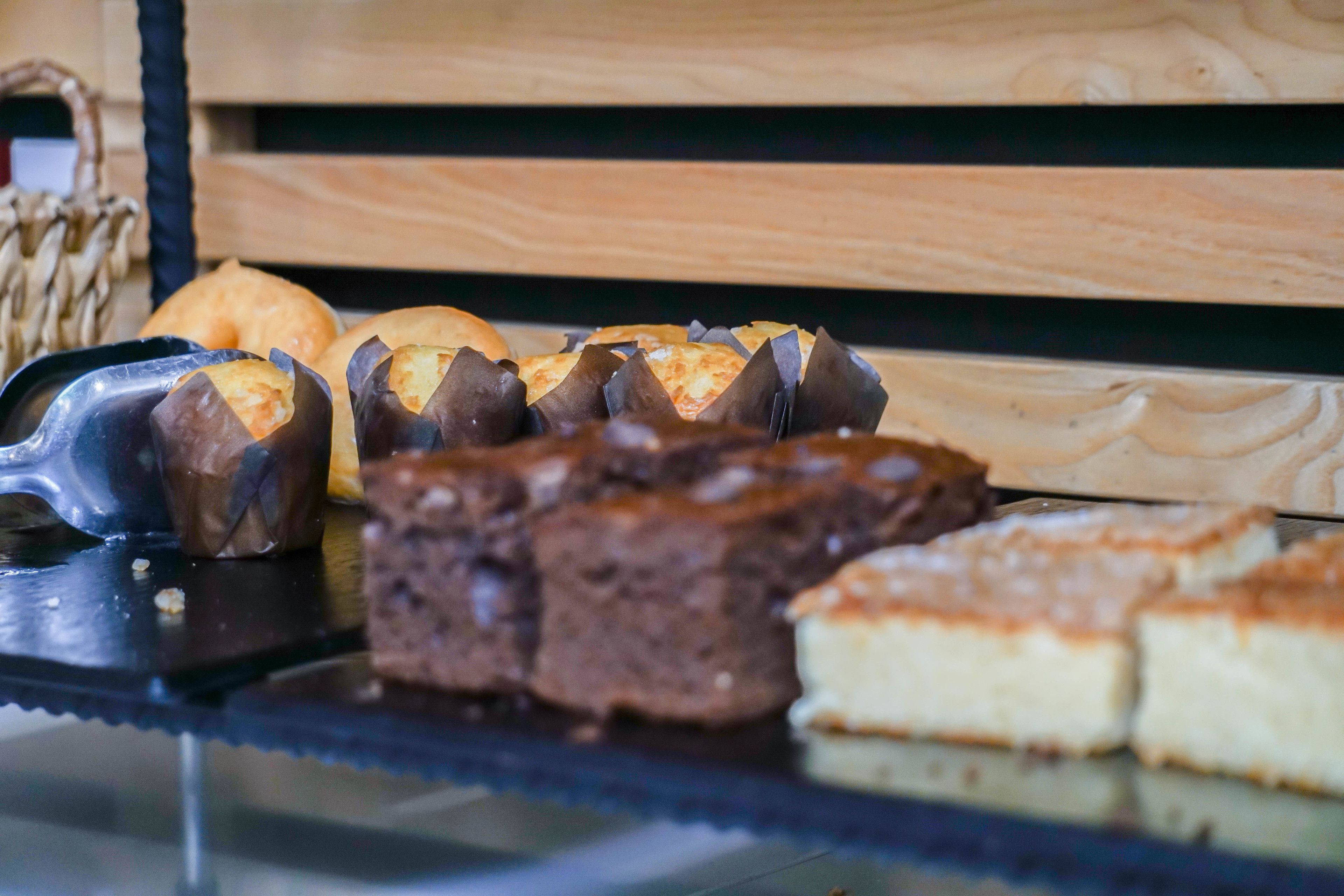 Una exhibición de varios productos horneados, incluyendo pasteles y tartas, sobre un mostrador de vidrio.