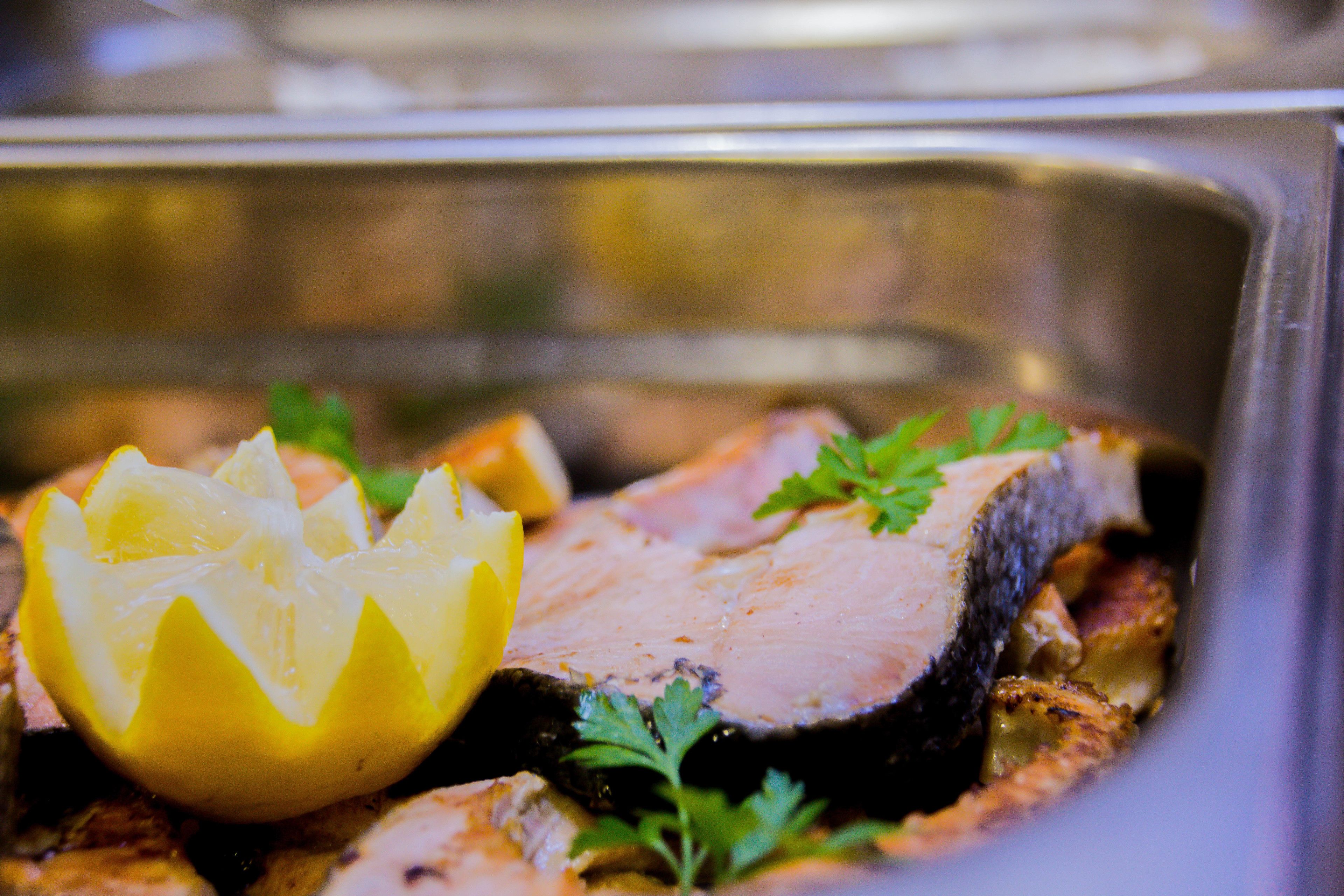 A close-up of a cooked dish with lemon slices and parsley garnish.