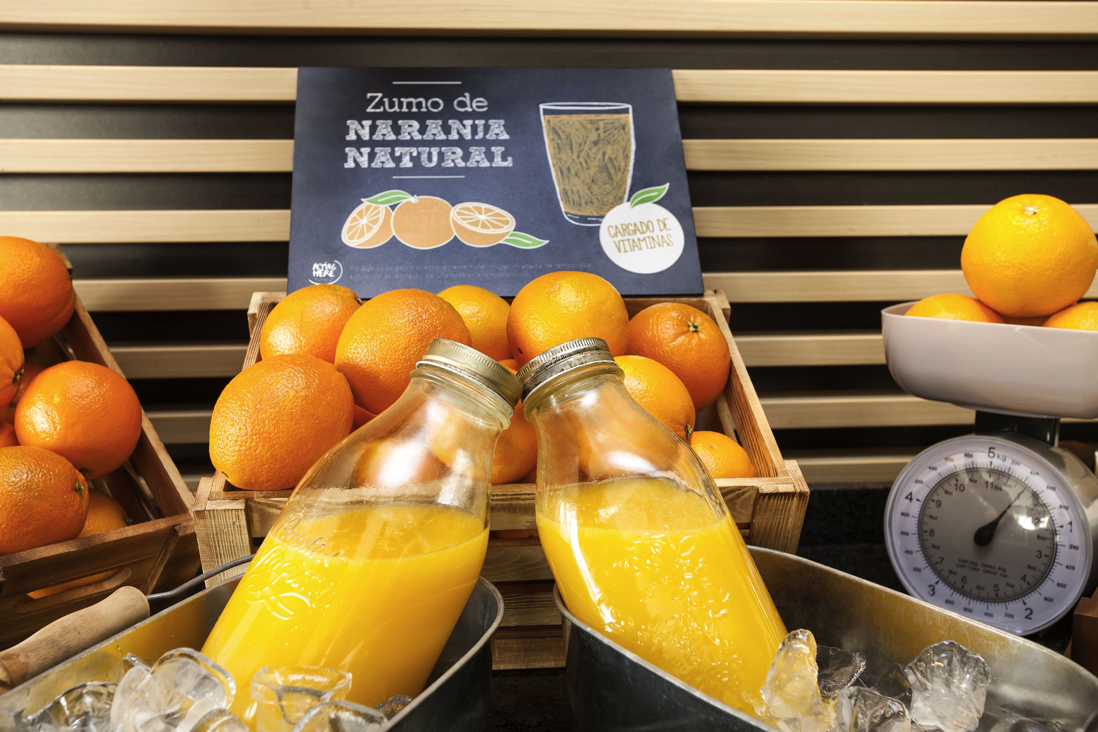A juice display with oranges and two bottles of orange juice.