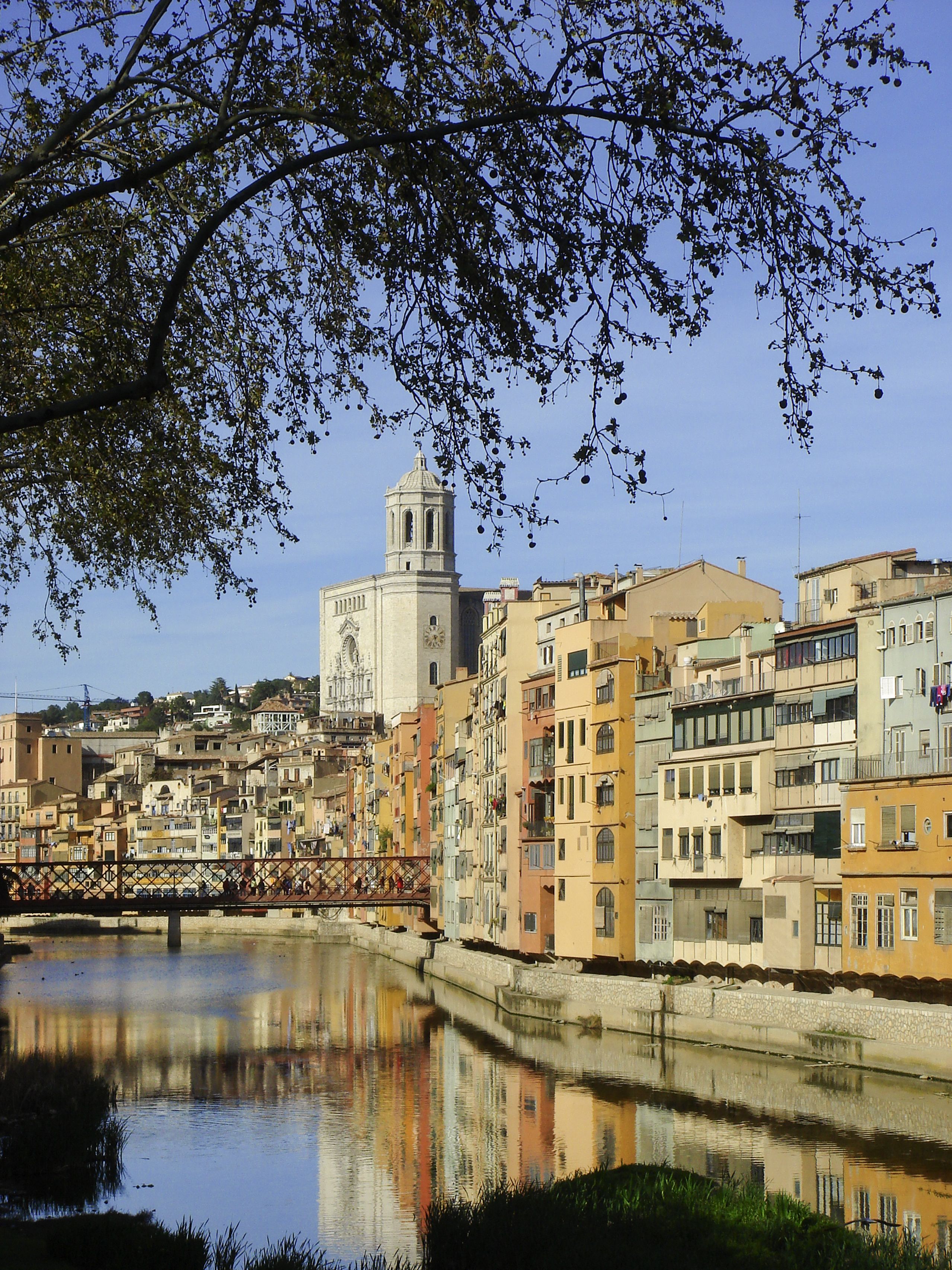 Un paisaje urbano histórico con una torre destacada, edificios que se reflejan y un río tranquilo.