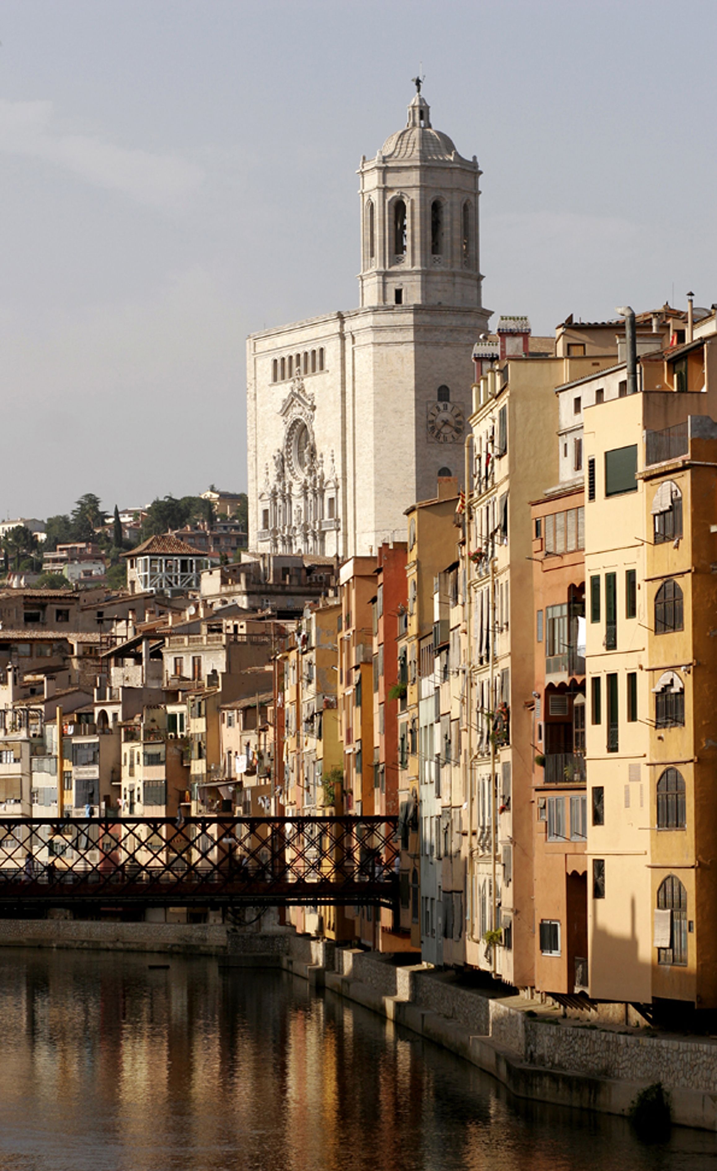 Un edificio histórico con una torre de reloj, rodeado de edificios coloridos que se reflejan en una masa de agua tranquila.
