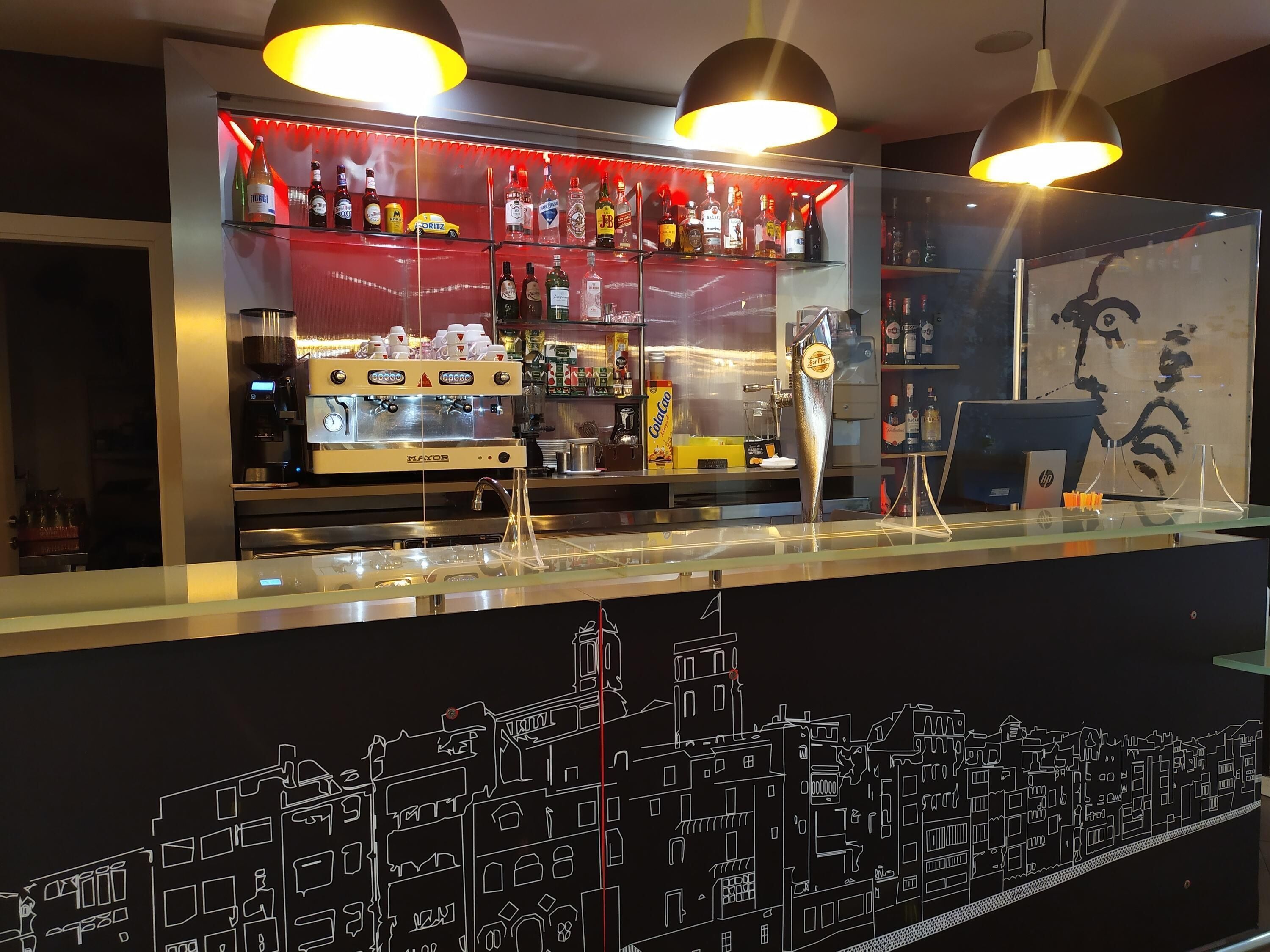 A bar area with a coffee machine, shelves of liquor, and a cityscape mural.