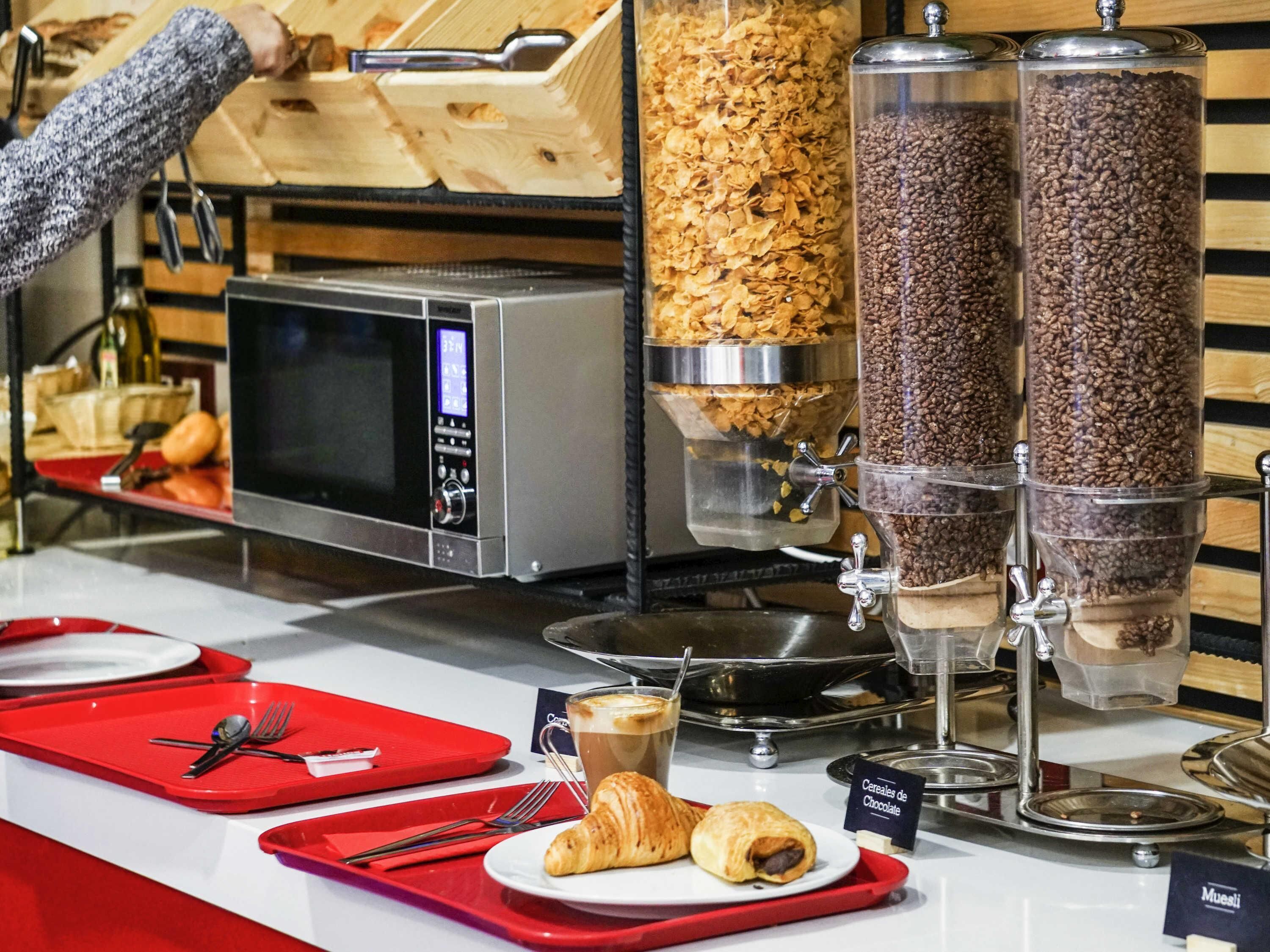 Un bufé de desayuno con cereales, café y pastelería.
