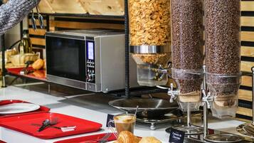 Un bufé de desayuno con cereales, café y pastelería.