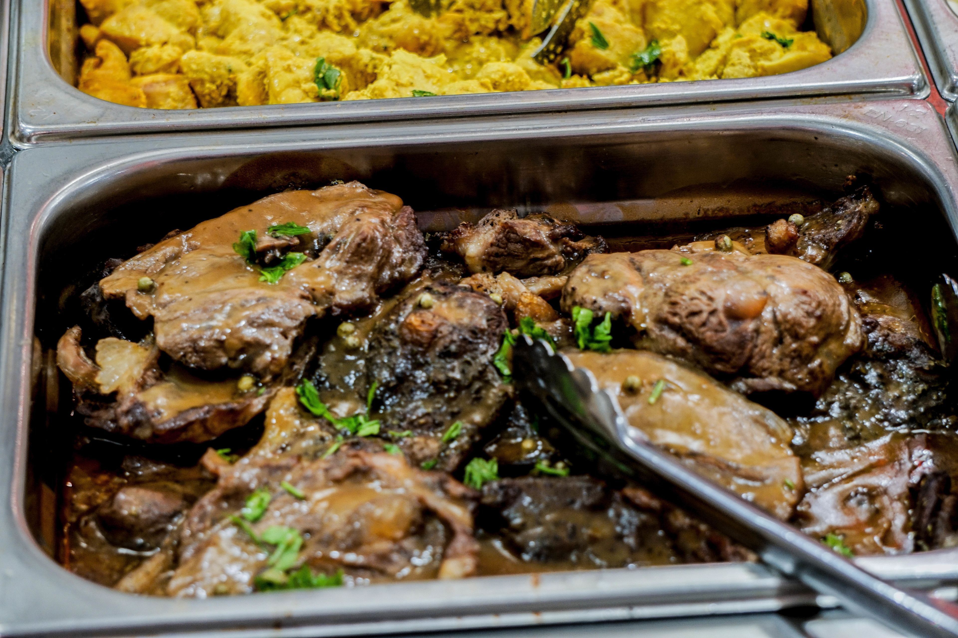 A buffet with various dishes including meat and a yellow dish.