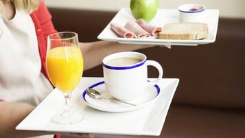 Una bandeja con un vaso de jugo de naranja, una taza de café, una rebanada de tostada, una loncha de jamón y una manzana.